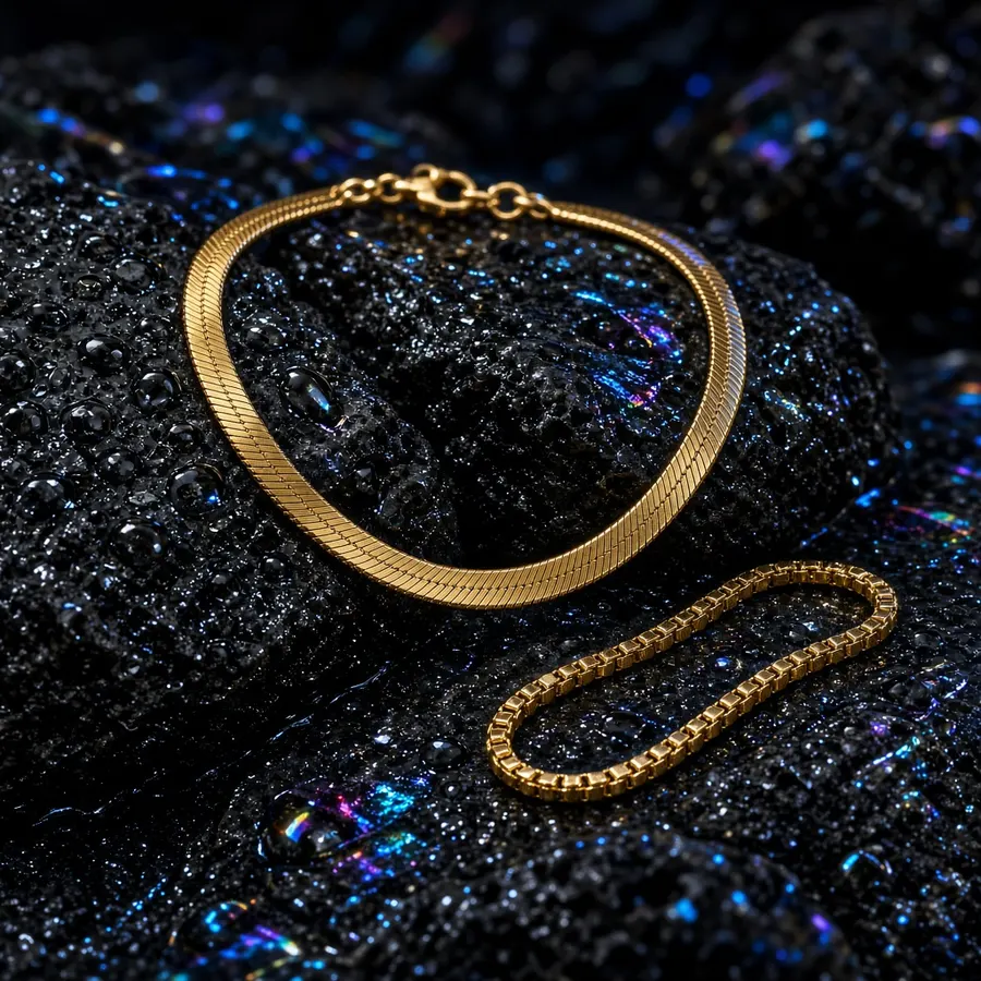 Two gold chains resting on dark iridescent fabric